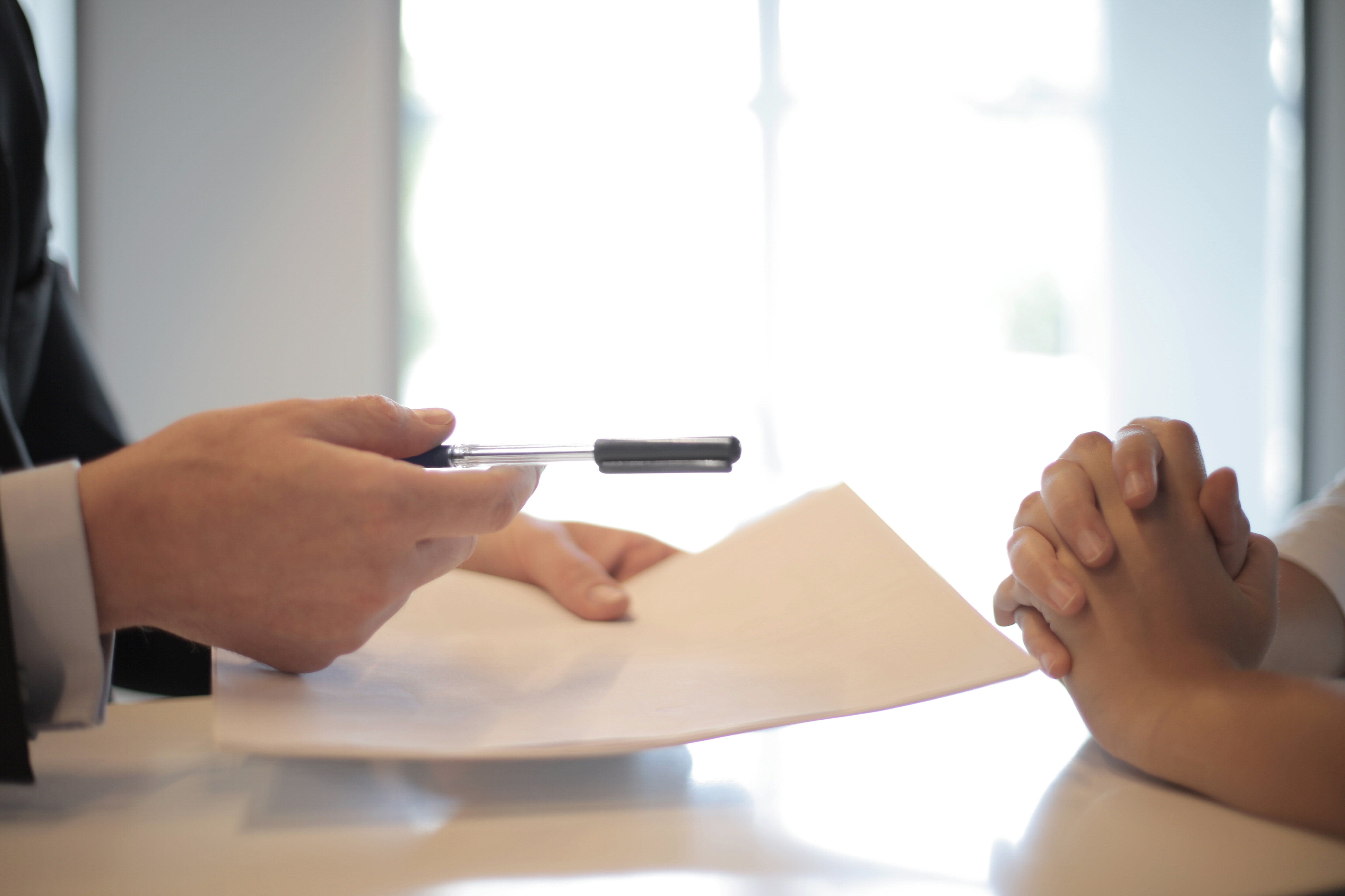 One person handing another person a pen and a paper.