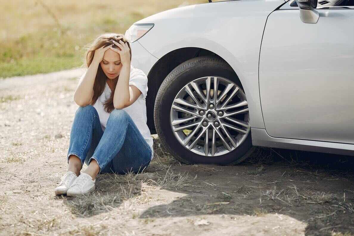 pexels-gustavo-fring-4173090(1) A stressed woman sitting on the ground next to her parked car.